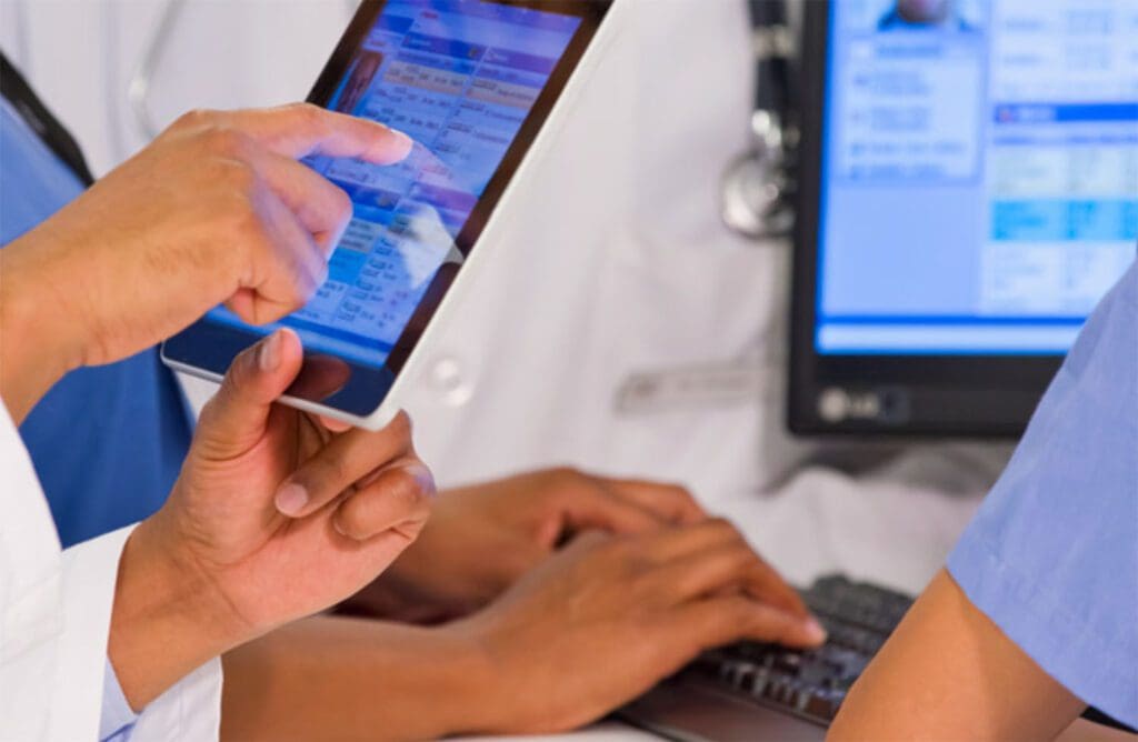 Doctor pointing at a tablet and talking to colleagues.