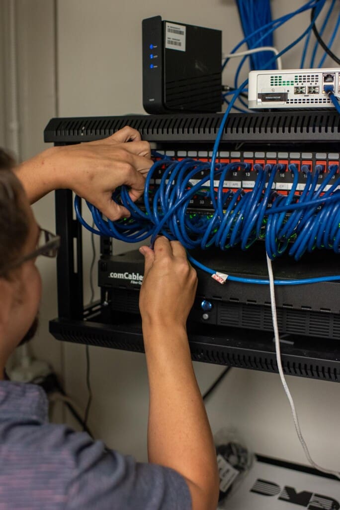 Close up of a Friendship Community Care associate working with technical wires in a server box.