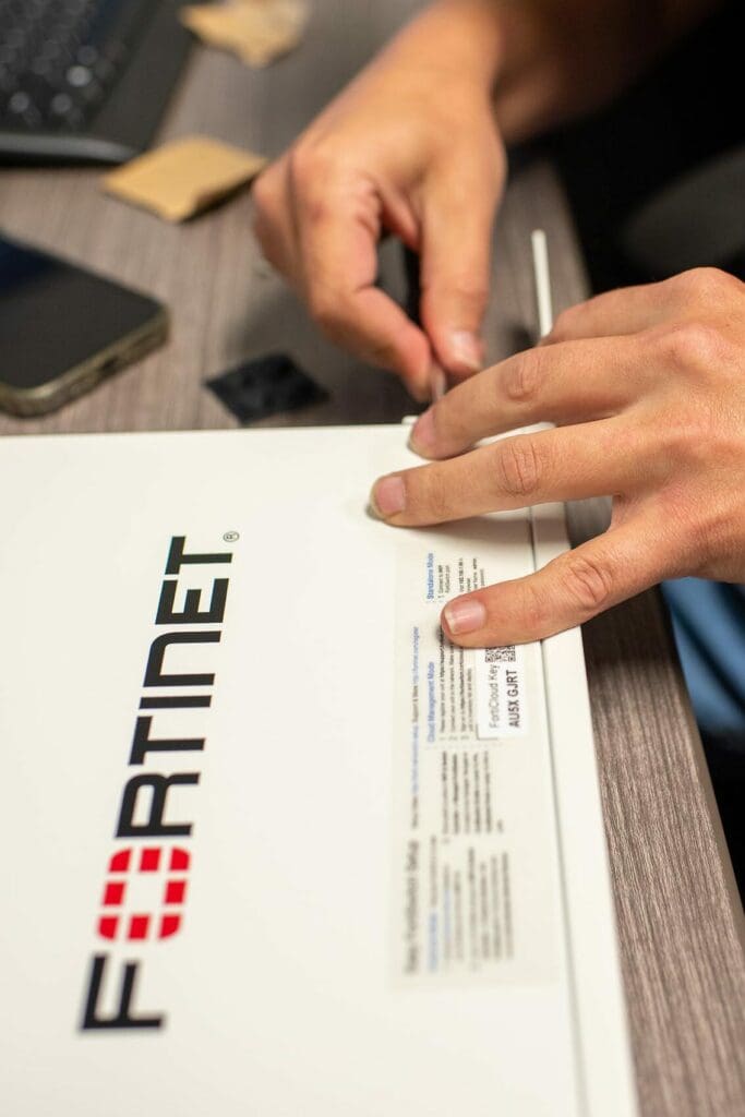 Close up photo of an Edafio associate fixing a a Fortinet box