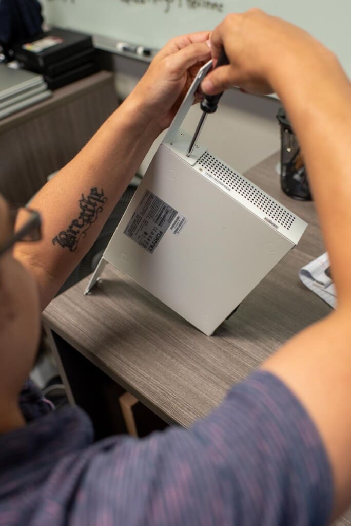 Close up photo of an Edafio associate fixing a Fortinet box with a screwdriver