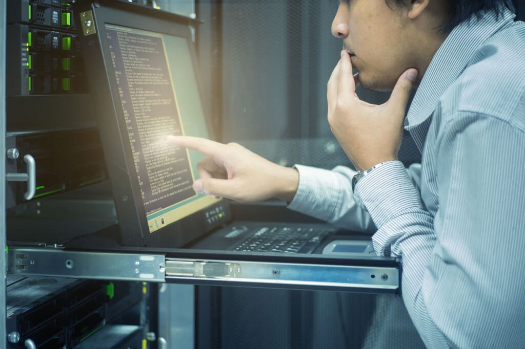 Man touching a laptop screen at a network rack